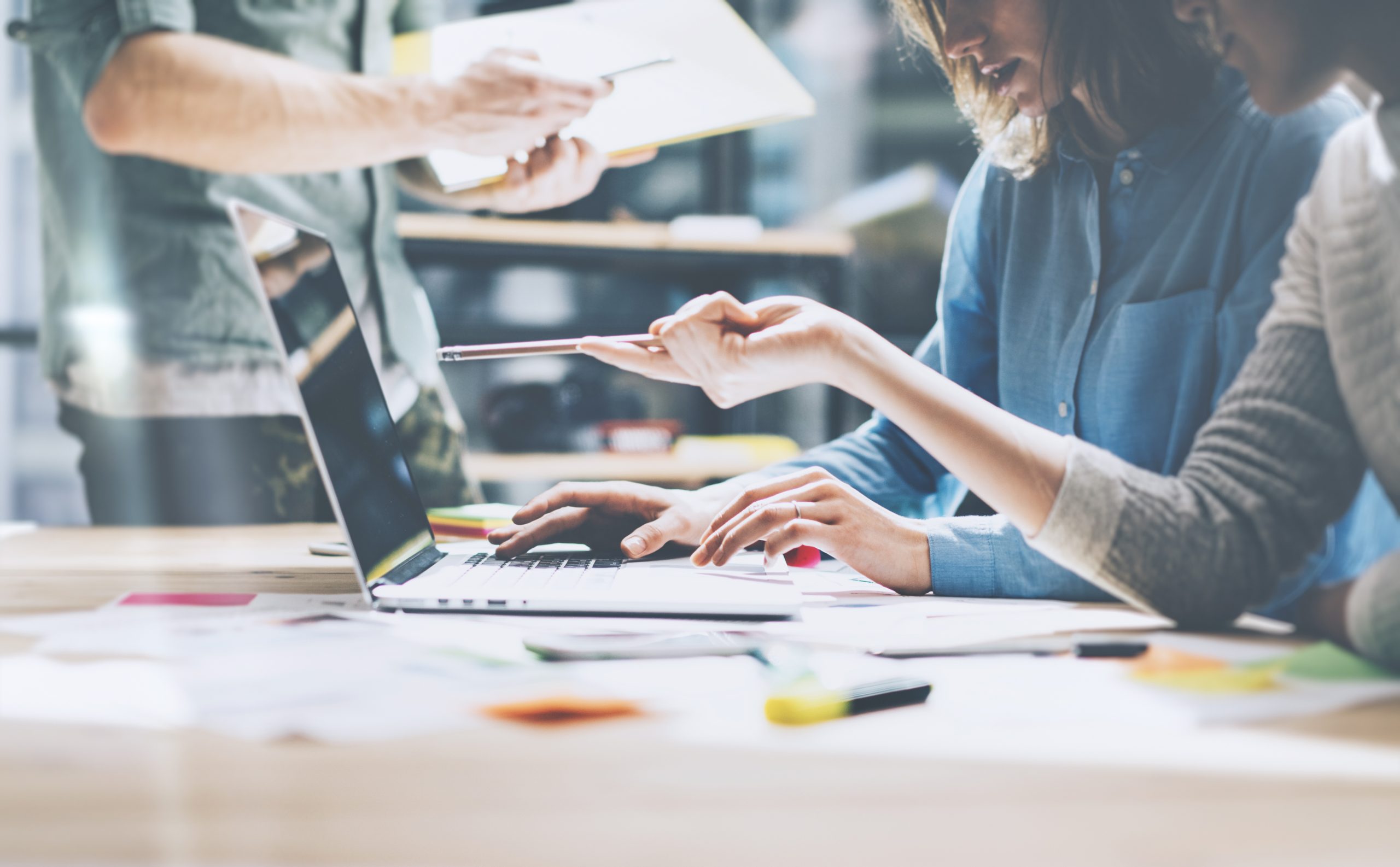 Dynamic team of professionals engaging in a collaborative workspace, analyzing affiliate marketing trends on a laptop, highlighting the proactive and strategic approach to staying ahead in digital marketing